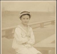 Young boy sitting on a box before a seaside backdrop