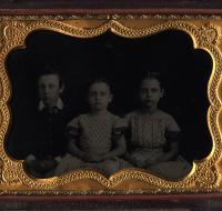 Cased tintype of a boy seated next to two girls in polka dot dresses